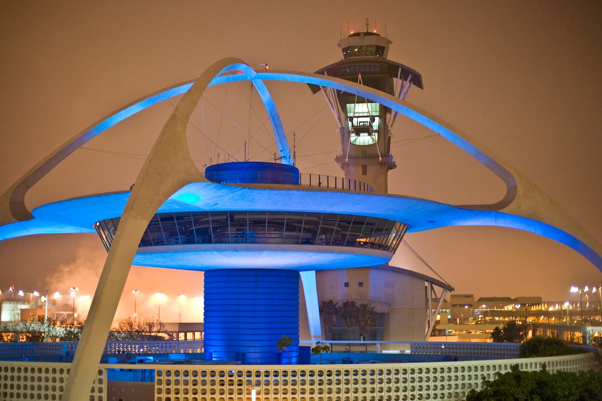 LAX Theme Building illuminated in blue with the airport control tower at night